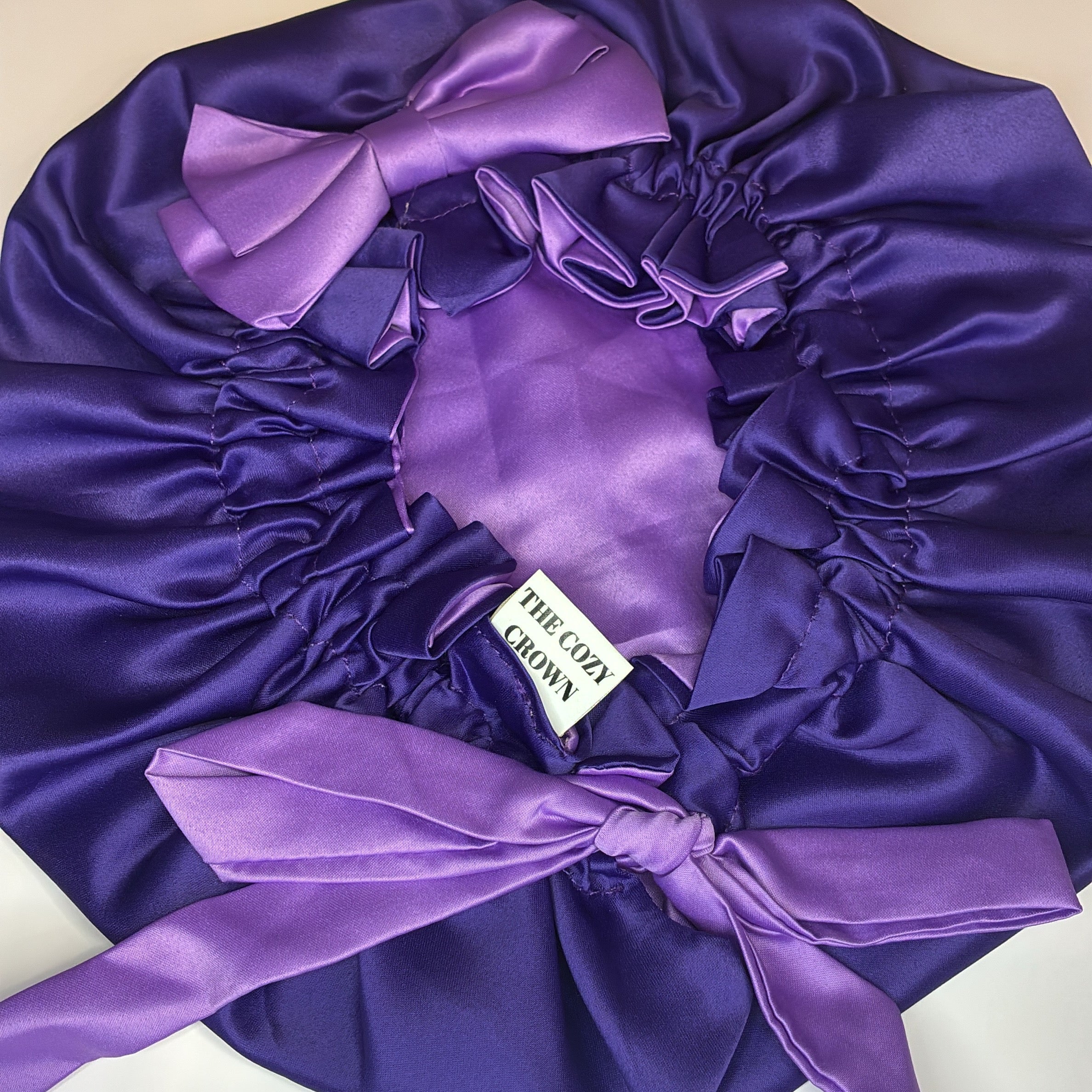 Purple satin bonnet with a bow on a white background